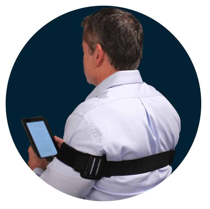 Image of a man wearing a PostureNOW posture corrector holding a tablet